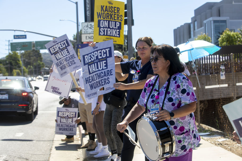 Kaiser workers stand along side of road with signs